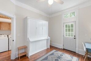 A room with a white wardrobe, a wooden bench, a patterned rug, and a door with frosted glass panels. - Charming Victorian 2BR Near Forsyth (Savannah)