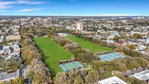 An aerial view of a cityscape with a large green park and tennis courts. - Charming Victorian 2BR Near Forsyth (Savannah)