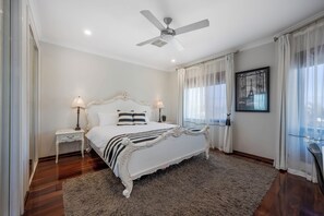 A bedroom with a large bed, two bedside tables, a ceiling fan, and a window with sheer curtains. - Hillside City-View Retreat with Pool & Alfresco, Near City (Dianella)