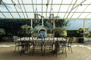 An outdoor patio with a table and chairs, surrounded by greenery and a corrugated metal roof. - Hillside City-View Retreat with Pool & Alfresco, Near City (Dianella)