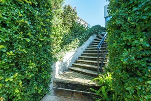 A stone staircase with a metal railing, surrounded by lush green foliage. - Hillside City-View Retreat with Pool & Alfresco, Near City (Dianella)