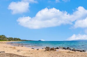 Una playa con cielos despejados y aguas tranquilas.