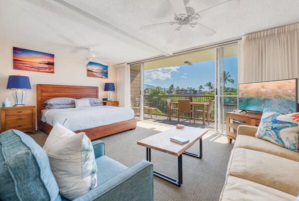 Een hotelkamer met een bed, een bank, een salontafel, een televisie en een balkon met uitzicht.