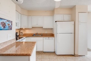 A kitchen with white cabinets, a double-door refrigerator, and a granite countertop. - Mana Kai 310: 2  BR, 2  BA Condominium in Kihei, Sleeps 4 (Kihei)