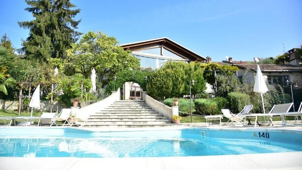 A swimming pool with lounge chairs, a staircase leading to a building, and surrounding greenery. - Ca' San Sebastiano Wine Resort & Spa 2 (Castel San Pietro)
