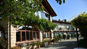 A courtyard with a stone building, potted plants, and a gravel path. - Ca' San Sebastiano Wine Resort & Spa 2 (Castel San Pietro)