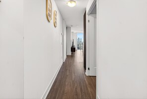 Een gang met uitzicht op de stad, houten vloeren en een deur naar een kamer.
