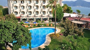 A hotel with a swimming pool, multiple balconies, and a view of the sea. - Hotel Mutlu  (Fethiye)
