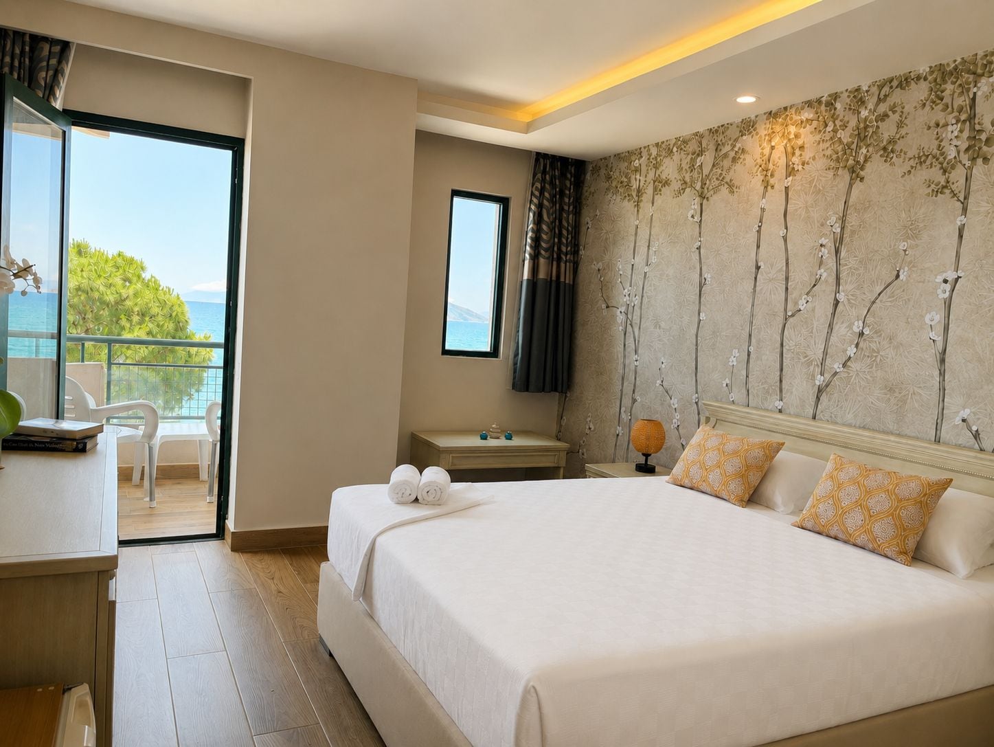 Ein Hotelzimmer mit einem Bett, einem Schreibtisch, einem Sessel, einem Fernseher und Blick aufs Meer.