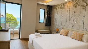 Ein Hotelzimmer mit einem Bett, einem Schreibtisch, einem Sessel, einem Fernseher und Blick aufs Meer.