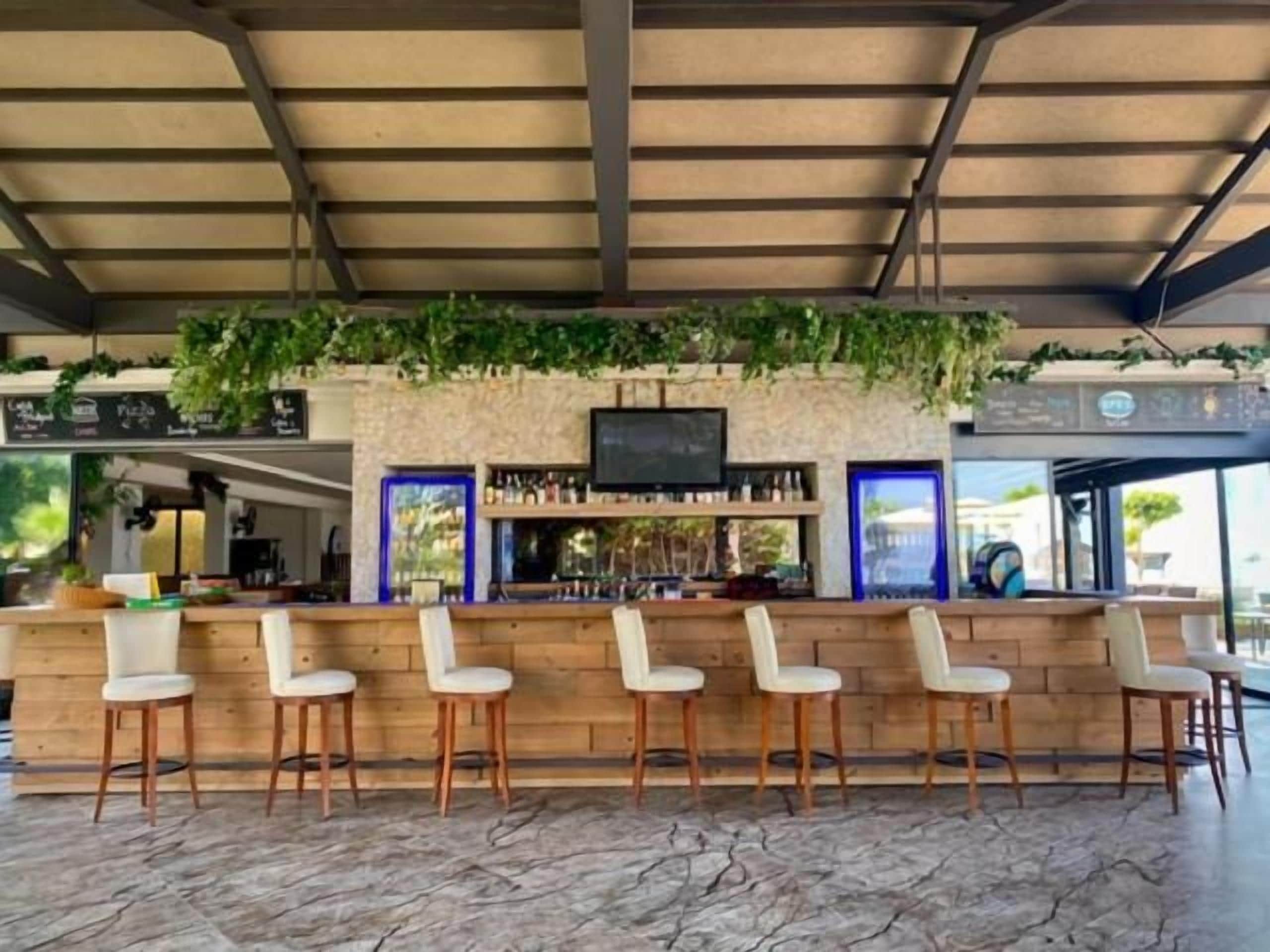 Eine Bar mit einer Steintheke, Holzkästen und einem Fernsehbildschirm.