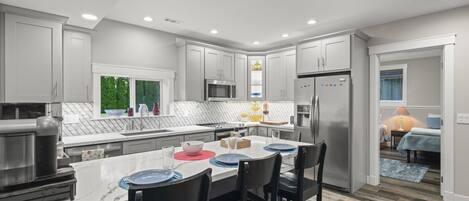 A modern kitchen with a central island, stainless steel appliances, and a dining area with bar stools.
