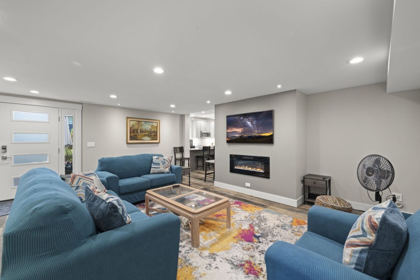 A modern living room with a blue sofa set, a glass coffee table, and a fireplace.