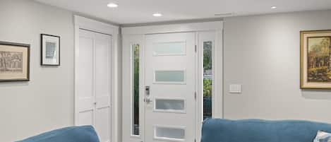A room with a white door, two blue sofas, and a framed picture on the wall.