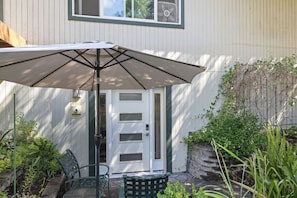 An outdoor patio with a table and chairs, a white door, and a fan on the wall. - Serene Kenmore Stay - 2BR, Patio & Parking (Kenmore)