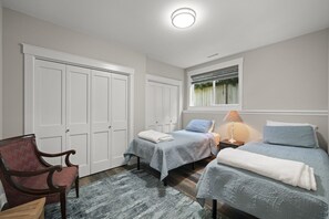 A bedroom with two beds, a chair, a window with blinds, and a ceiling light. - Serene Kenmore Stay - 2BR, Patio & Parking (Kenmore)