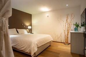 Ein Schlafzimmer mit Bett, Nachttisch, Lampe und Zimmerpflanze.