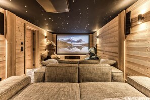 Ein gemütliches Zimmer mit einem großen Bildschirm, bequemen Sitzgelegenheiten und Holzwänden.
