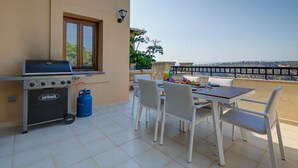 An outdoor patio with a grill, dining table, chairs, and a view of the sea. - Junior Villa EZ02 - Minimi (Kouklia)