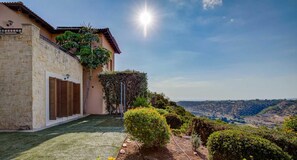 A house with a stone facade, wooden shutters, and a garden with various plants and a small water feature. - Junior Villa EZ02 - Minimi (Kouklia)