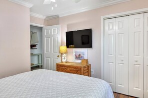Un dormitorio con cama, cómoda, televisor y armario.