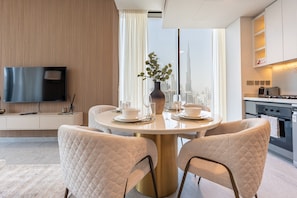 A modern dining area with a round table, two chairs, and a view of a cityscape. - 40th+ Floor 1BR w/ Burj Khalifa & Canal Views, Spacious Balcony, Near Downtown (Dubai)