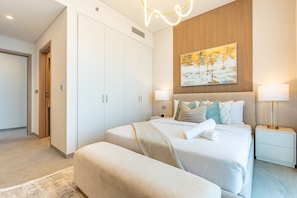 A modern bedroom with a large bed, bedside tables, a bench, and a painting on the wall. - 40th+ Floor 1BR w/ Burj Khalifa & Canal Views, Spacious Balcony, Near Downtown (Dubai)