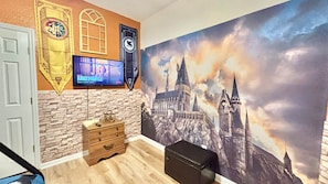A room with a stone wall, a wooden dresser, a black ottoman, and a large Hogwarts-themed wall mural. - Ref 519. 5 Bedroom villa own pool/spa. Recent refurb. Disney (Osceola County)