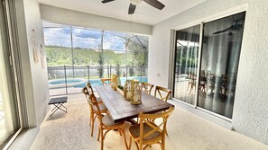 A spacious patio with a wooden table and chairs, a glass door leading to an outdoor area, and a view of a swimming pool. - Ref 519. 5 Bedroom villa own pool/spa. Recent refurb. Disney (Osceola County)