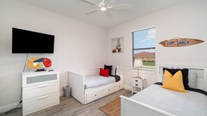 Ein Schlafzimmer mit einem Bett, einem Schreibtisch, einem Stuhl, einem Fernseher und einem Wandbild.