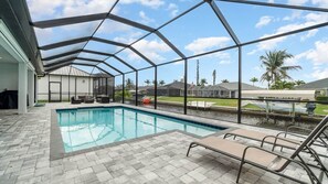 Ein Schwimmbad mit überdachter Terrasse, einer Liege und Blick auf die umliegende Nachbarschaft.