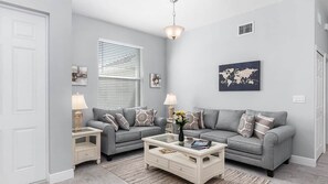 A living room with two grey sofas, a white coffee table, and a world map artwork on the wall. - Ref 901. Cape Coral villa, free heated pool. Pet friendly (Cape Coral)