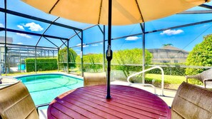 Un espacio al aire libre techado con piscina, asientos y vistas del paisaje circundante.