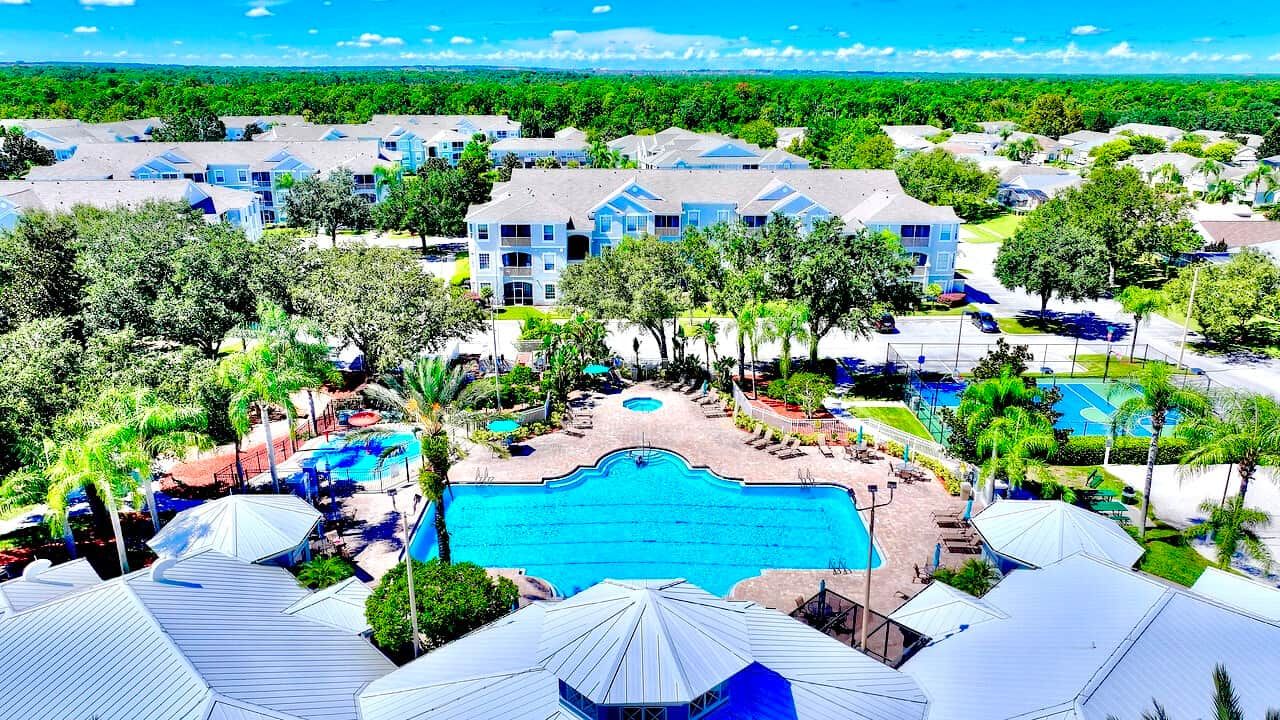 Ein Resort mit mehreren Gebäuden, einem zentralen Schwimmbad und umliegender Bepflanzung.