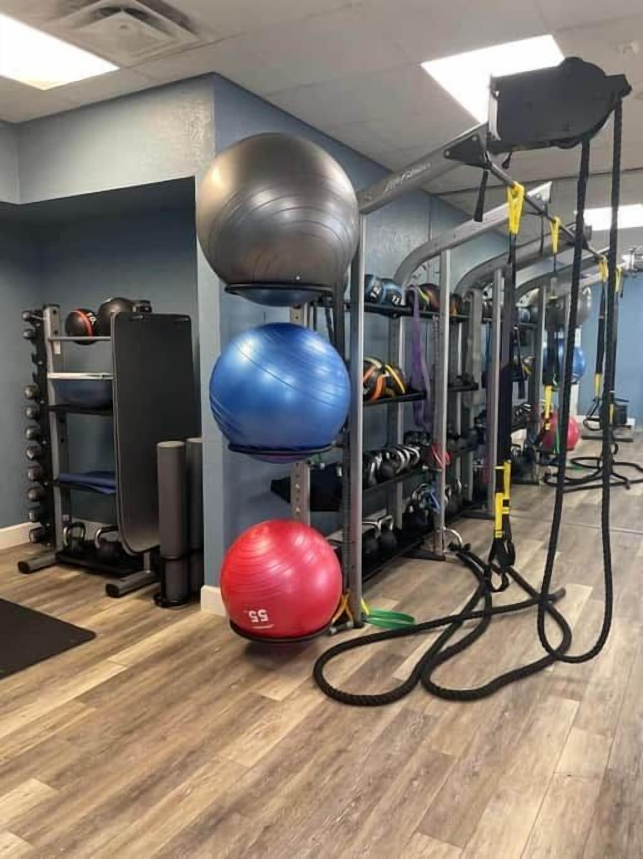 Een sportschool met trainingsapparatuur, waaronder een squatsrek, medicijnballen en een bank.