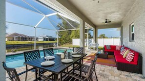 A covered patio area with a pool, dining table, and seating. - ref 900. 4 bedroom Cape Coral waterfront villa. Own pool (Cape Coral)