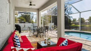 An indoor patio area with a pool, red seating, and a glass enclosure. - ref 900. 4 bedroom Cape Coral waterfront villa. Own pool (Cape Coral)