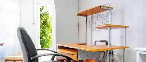 Una habitación con escritorio, silla y estantería.