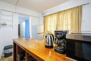 Una cuina compacta amb taula de fusta, cafetera i bullidora.