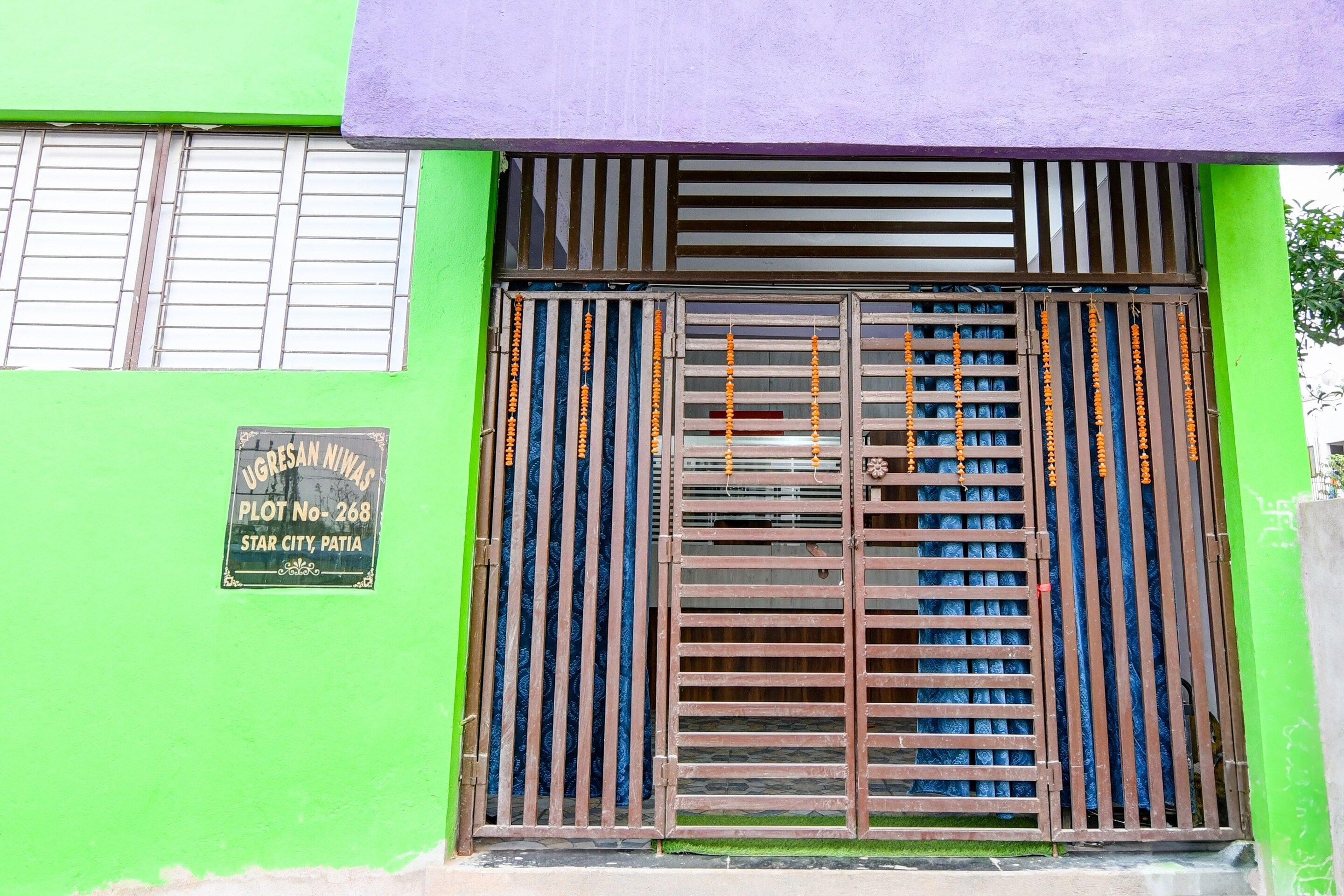 A green building with a metal gate and a sign indicating 'UGRESAN NIWA'S PLOT NO-268 STAR CITY, PATIA'.