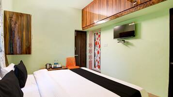 A hotel room with a bed, a television mounted on the wall, and a window with a view of the outside.