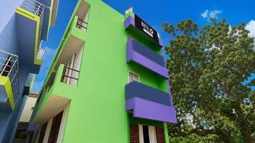 A multi-story hotel with a green facade, balconies, and a flag on top.