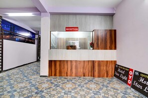 A reception desk with a 'RECEPTION' sign, a wooden counter, and a window with blinds. - Deluxe Room Star Light (Bhubaneshwar)