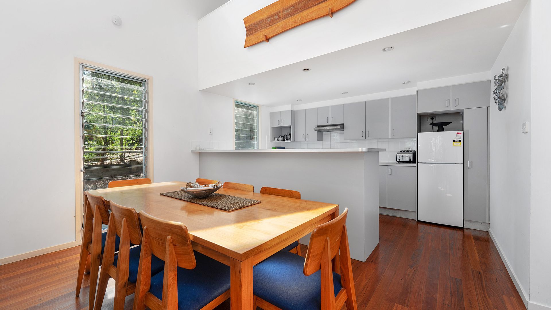A modern kitchen with white cabinets, a built-in oven, and a refrigerator.