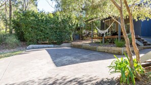 A paved driveway leading to a wooden deck with a hammock and a chair. - Boathouse 1 by Experience Jervis Bay (Hyams Beach)