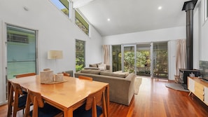 A modern interior with a wooden dining table, a sofa, and a TV.