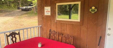 A wooden cabin with a red table, two chairs, a sign reading 'Floyd Cabin,' a framed picture, and a door with a coat of arms.