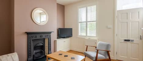 Una sala de estar con chimenea, televisor, sofá, mesa de centro y puerta con ventana.