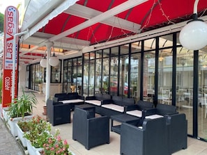 An outdoor seating area with wicker furniture and a red awning. - Hotel LAS vegas  (Riccione)