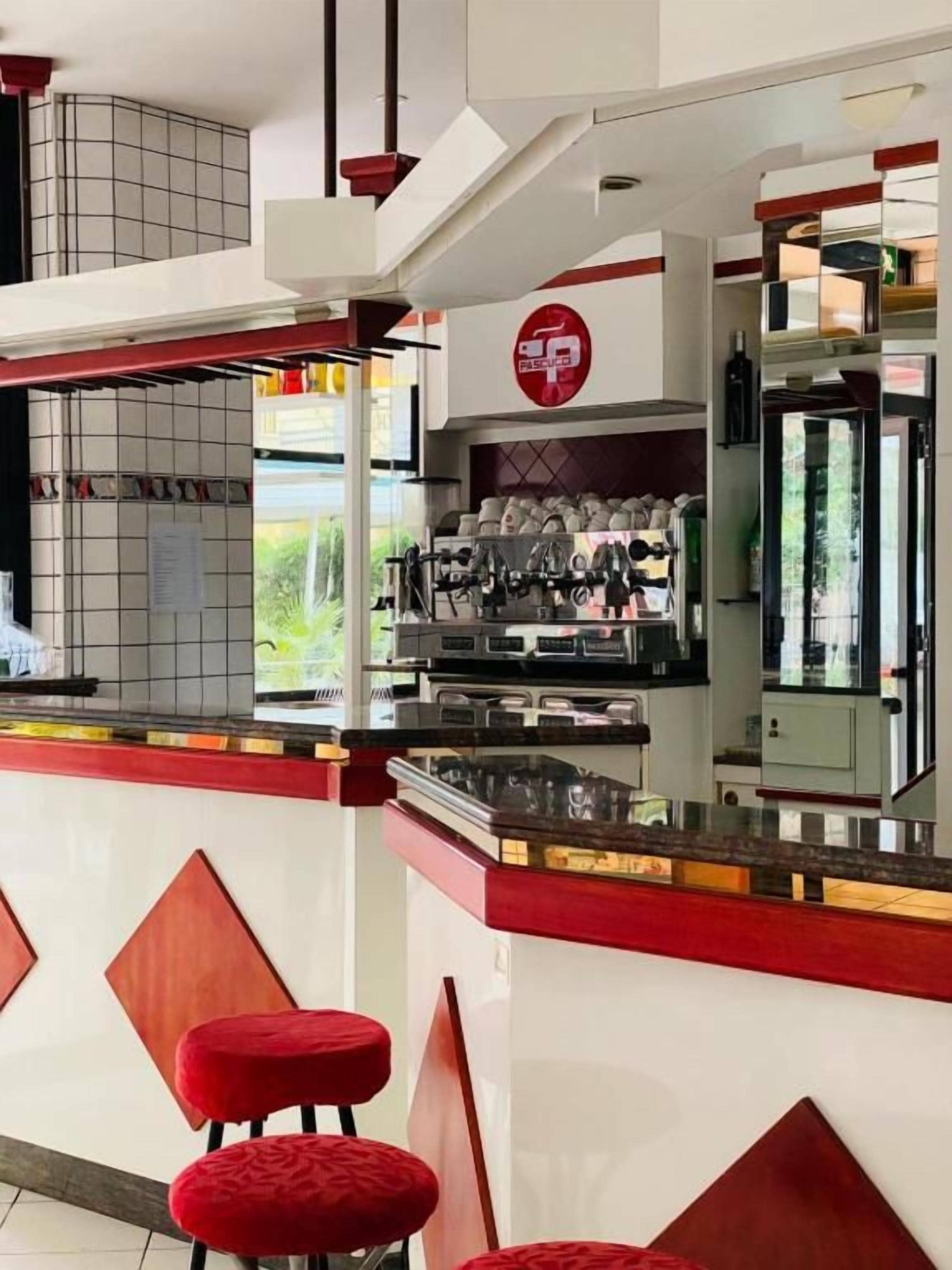Une cuisine moderne avec un coin bar, des tabourets de bar rouges et une machine à café.